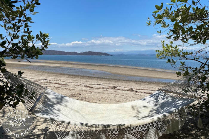 hammock over sand near calm bay mountain background